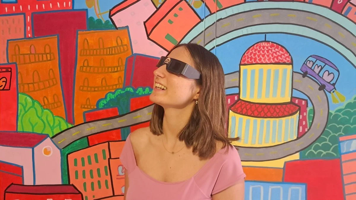 Imagen ilustrativa: vista de un balcón urbano con el cielo despejado y el sol parcialmente eclipsado, con la calle al fondo.