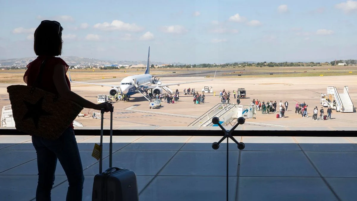 Illustrative image: interior of an airport with departure panel and travellers in the background