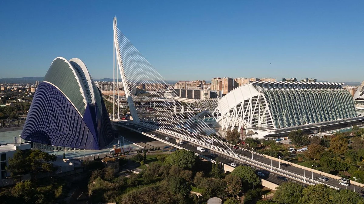 Imagen ilustrativa: puente atirantado con pilón blanco sobre un parque urbano, con algunos peatones de espaldas a lo lejos.
