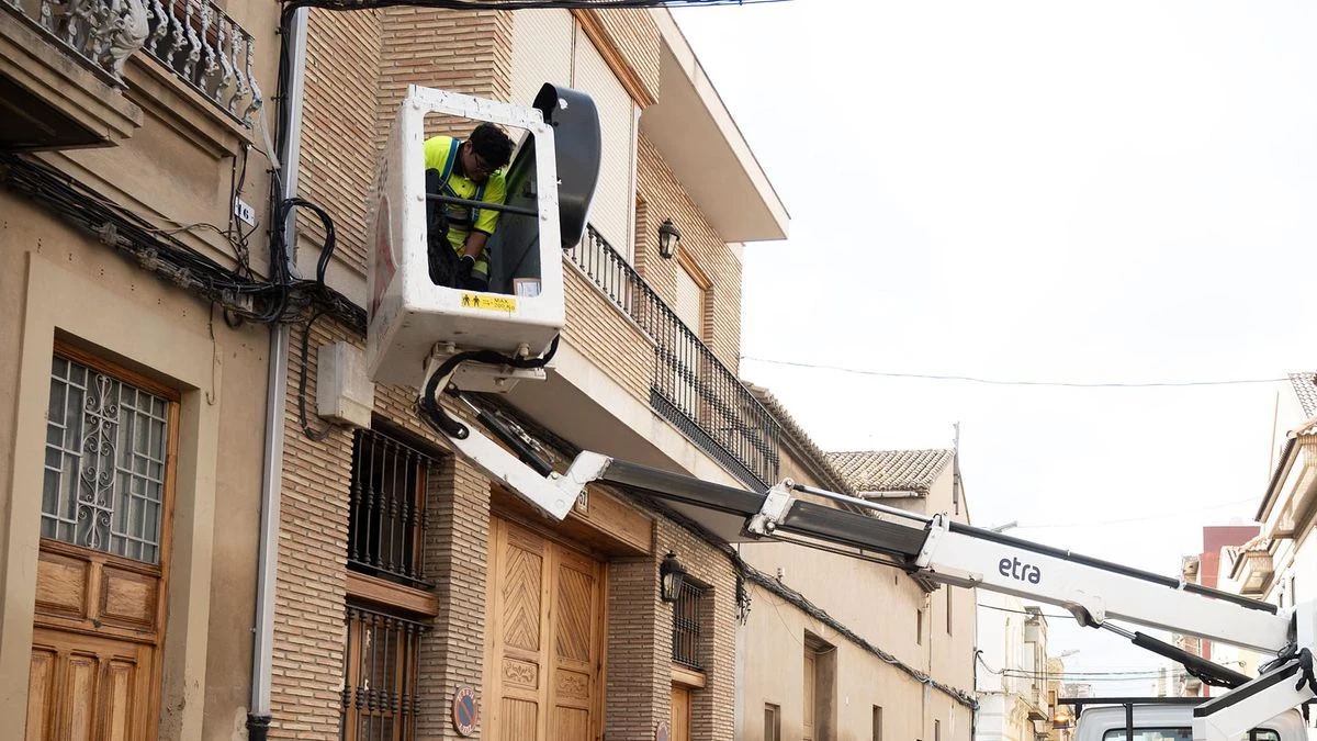 Imagen ilustrativa: calle de un pueblo con farolas antiguas y nuevas luces LED en proceso de instalación, sin personas reconocibles.