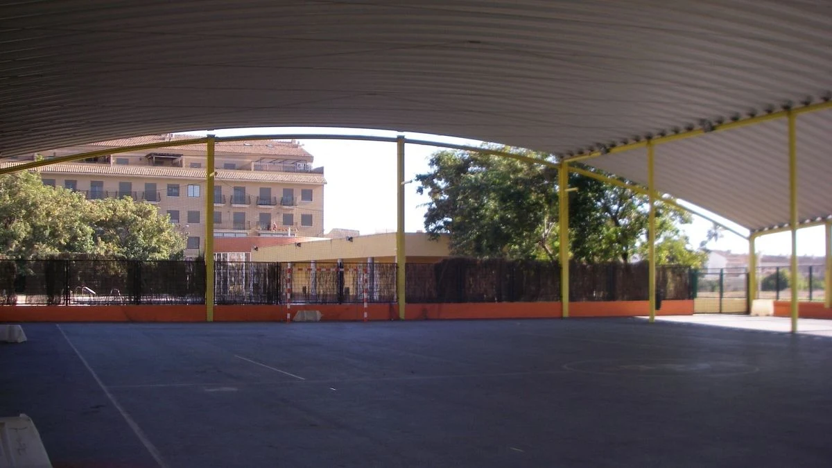 Imagen ilustrativa: una pista deportiva al aire libre con canasta y valla perimetral en un barrio residencial.