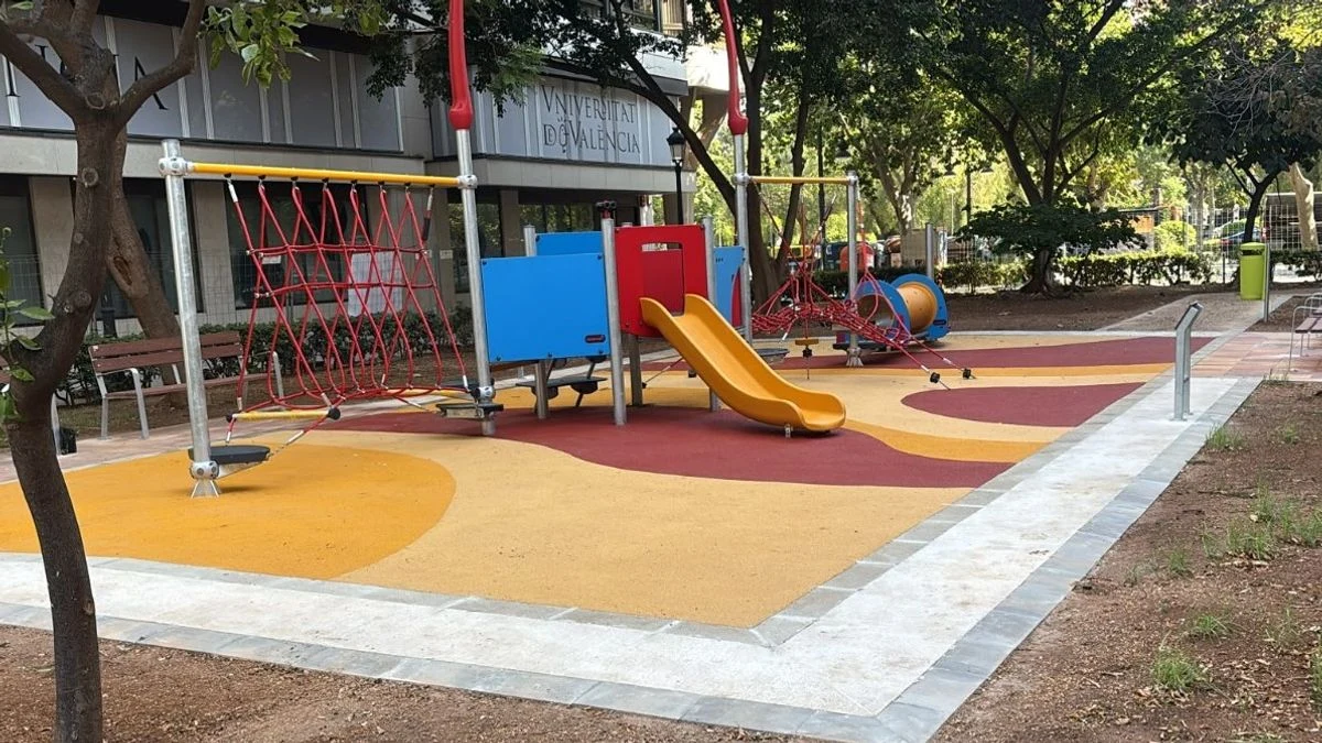 Imagen ilustrativa: parque infantil con columpios y tobogán en una zona verde urbana, con árboles y setos alrededor.