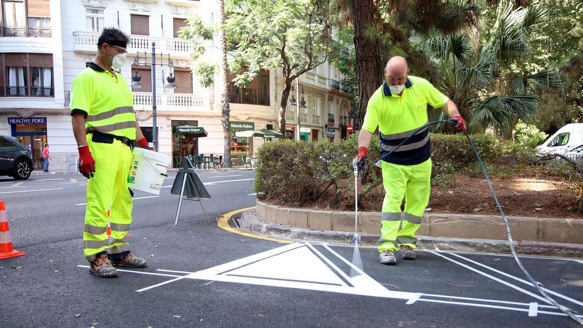 Imagen ilustrativa: una calle ancha recién asfaltada con un trabajador y una máquina compactadora al fondo