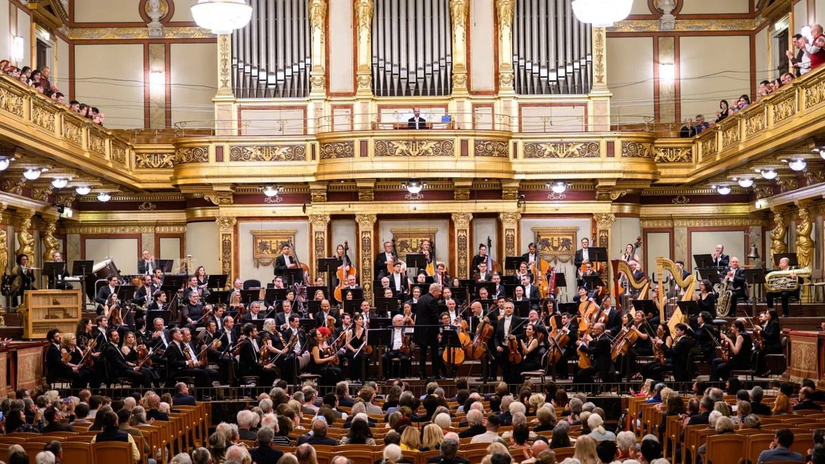 Imagen ilustrativa: interior de una sala de conciertos vacía con butacas rojas y un atril sobre el escenario